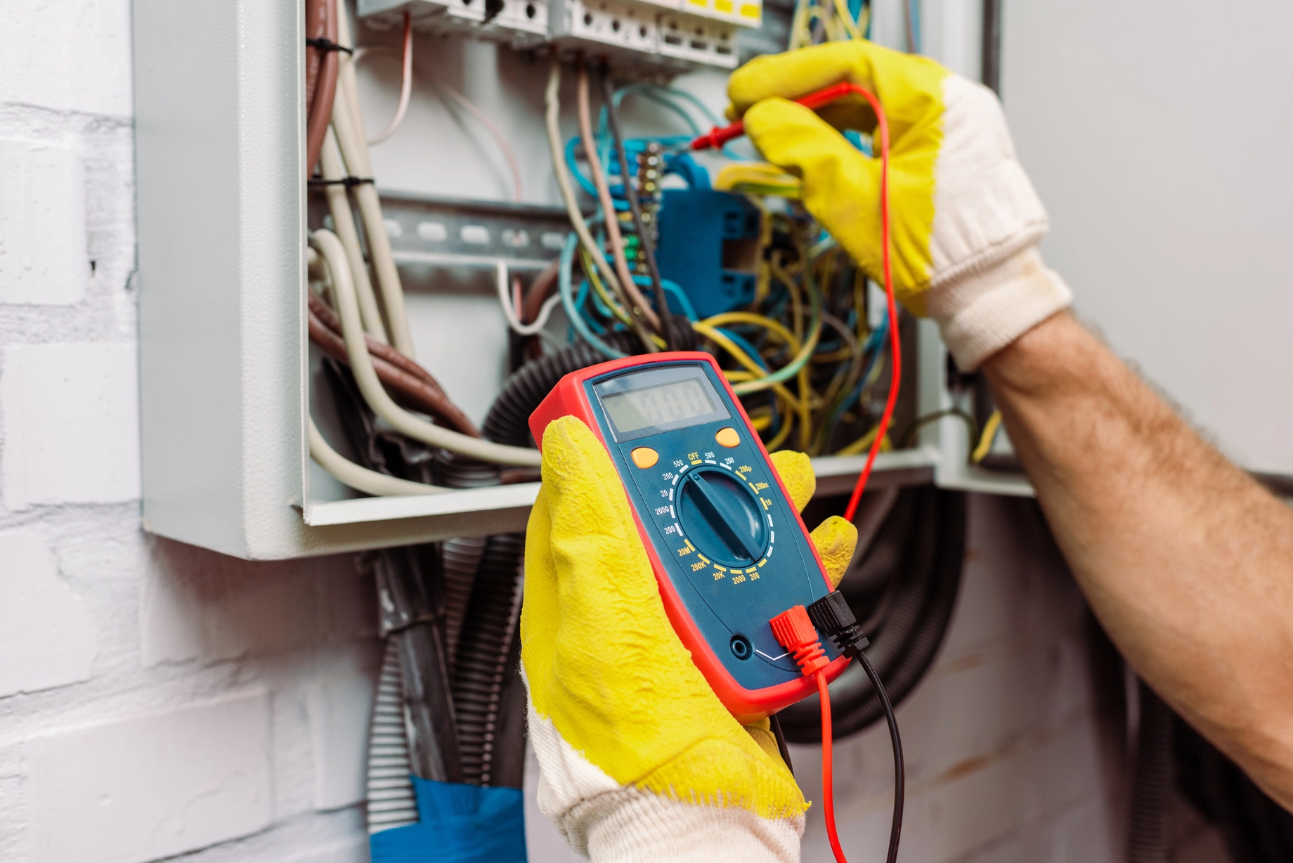 Elektriker misst beim E-Check die Spannung im Verteilerkasten mit dem Messgerät